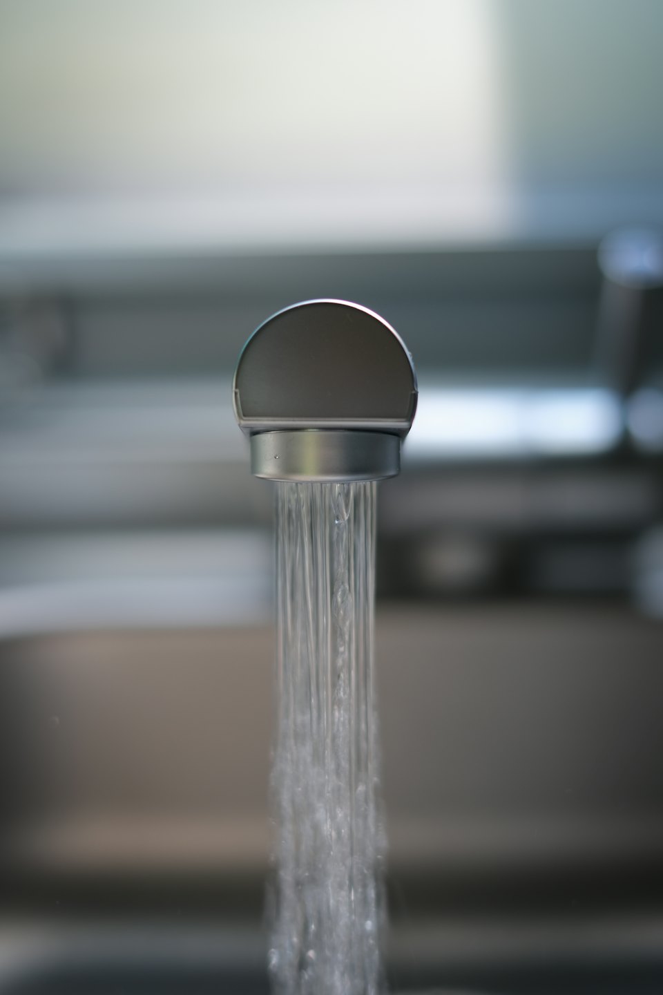 Chrome kitchen faucet with a stream of clear water.
