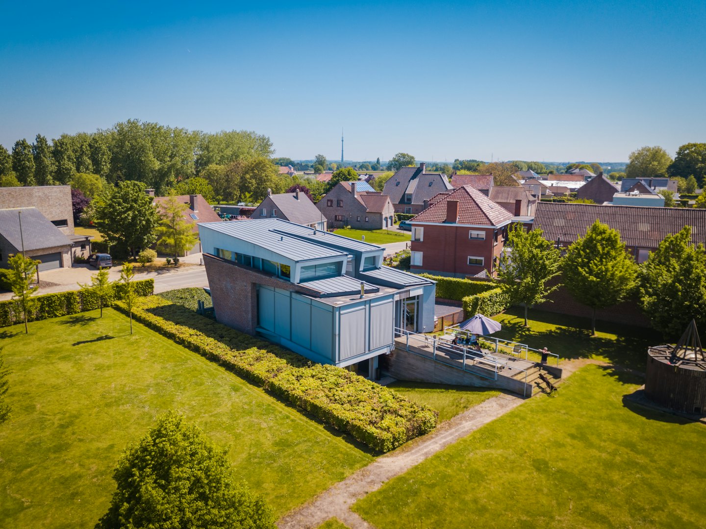 Modern house with a grey roof sits in a neighborhood.